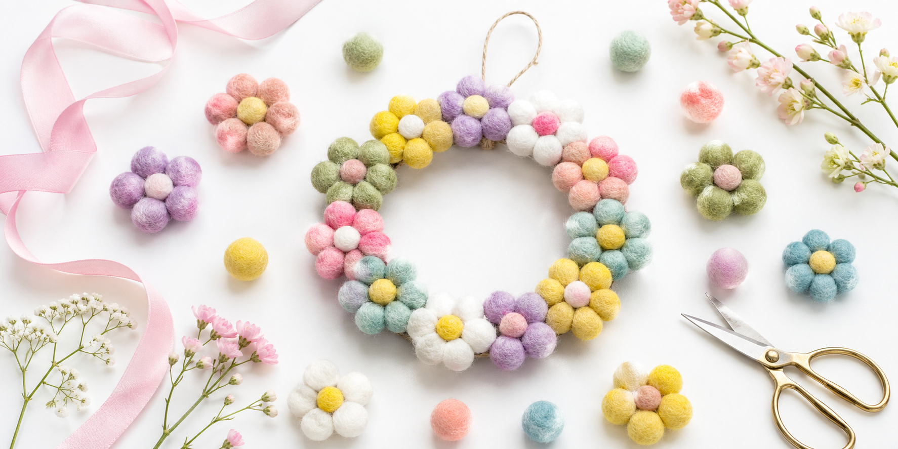 Bright flat lay of spring felt products including pastel felt balls, flower shapes, and a small wreath